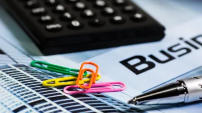 Calculator, colorful paperclips and a pen on a business report, illustrating how small businesses measure AI financial payoff.