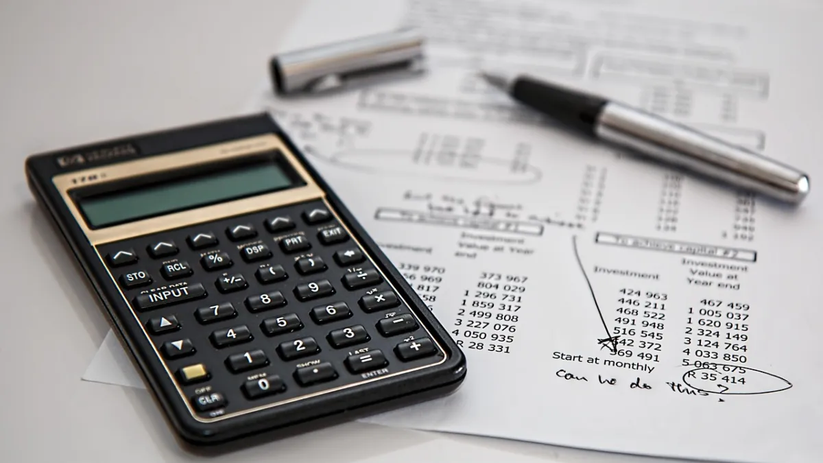 Calculator and pen on financial documents and invoices on a desk, illustrating an n8n invoice reminder automation tutorial