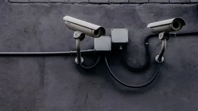 Two CCTV security cameras mounted on a concrete wall, evoking AI agent safety monitoring