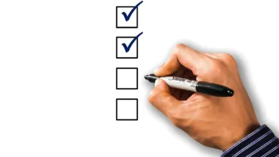 A hand ticking off a checklist with a pen, illustrating the steps to test Claude Skill before giving it to your team