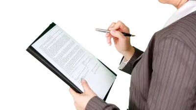 Businesswoman reviewing documents on a clipboard — reviewing a company SOP before turning it into a Claude skill