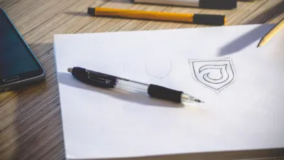 Designer sketching logo concepts on paper at a creative desk — best AI logo makers for startups