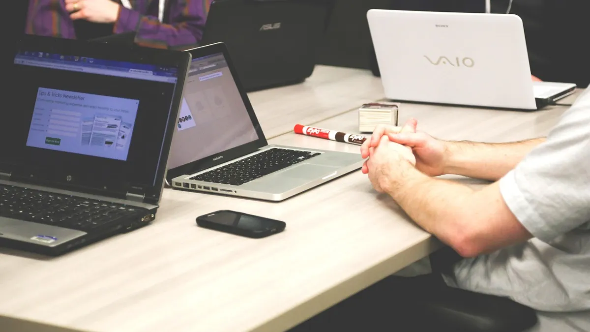 Coworkers with laptops in a modern office meeting, illustrating the best AI Chrome extensions for small teams