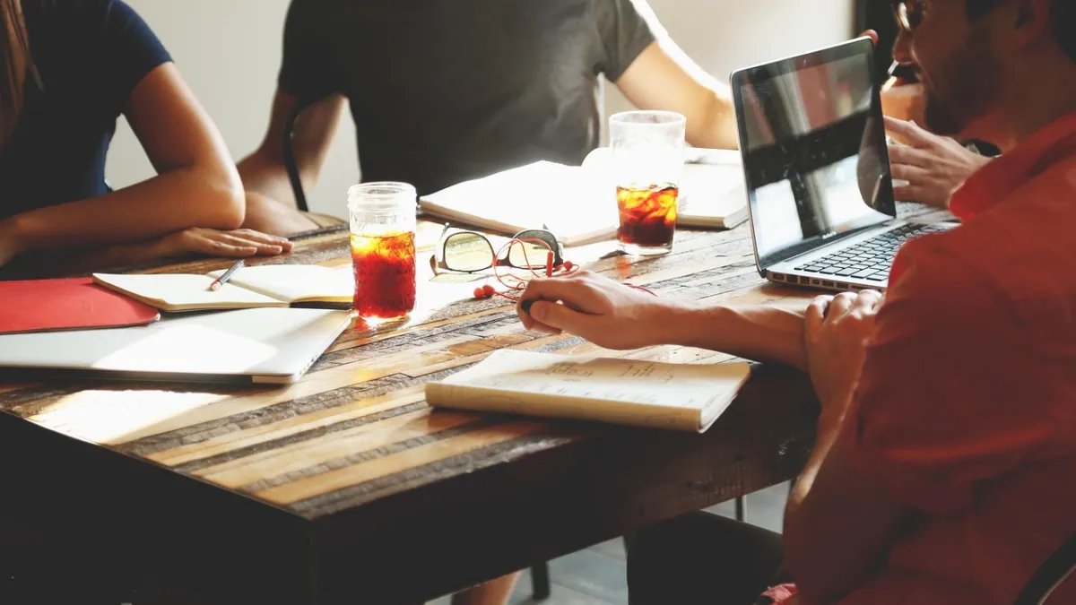 Casual team meeting around a table with a laptop and notebooks in a modern office, representing AI assistants in productivity suites