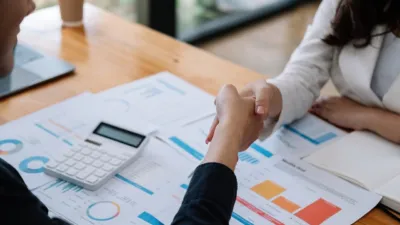Business team shaking hands over financial reports and charts on a desk — Perplexity vs ChatGPT for business research comparison