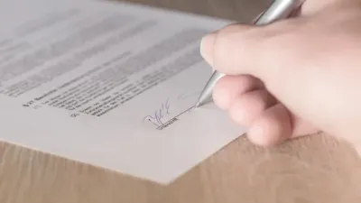 Hand signing a business contract with a pen, as Meta revises its AI training terms.