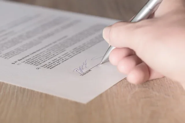 Hand signing a business contract with a pen, as Meta revises its AI training terms.