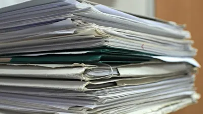 Stack of office documents and folders on a desk to summarize PDFs with AI