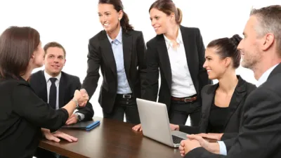 Two businesspeople shaking hands over a deal, illustrating OpenAI discounts to win Anthropic customers