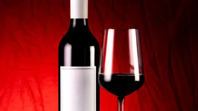 Red wine bottle and filled wine glass styled against a deep red backdrop — an example of AI product photos for an online store.