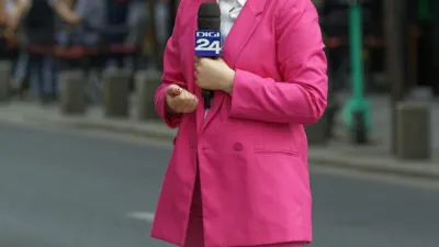 TV reporter in a pink suit with microphone on a Bucharest street, illustrating a presenter for a HeyGen review