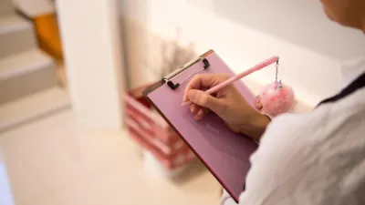 Hand writing notes on a pink clipboard — documenting a checklist when you create a Claude skill